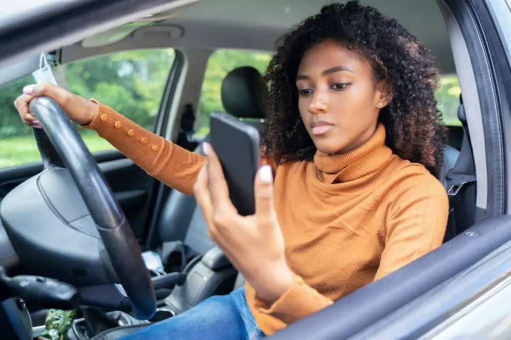 Une jeune dame se laisse distraire au volant par son téléphone lors d'un voyage en voiture.