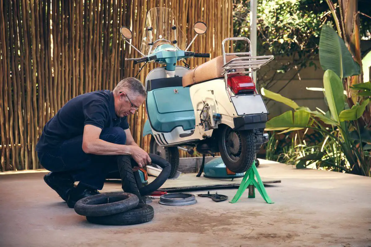 Un homme assure l'entretien et la réparation de son scooteur.